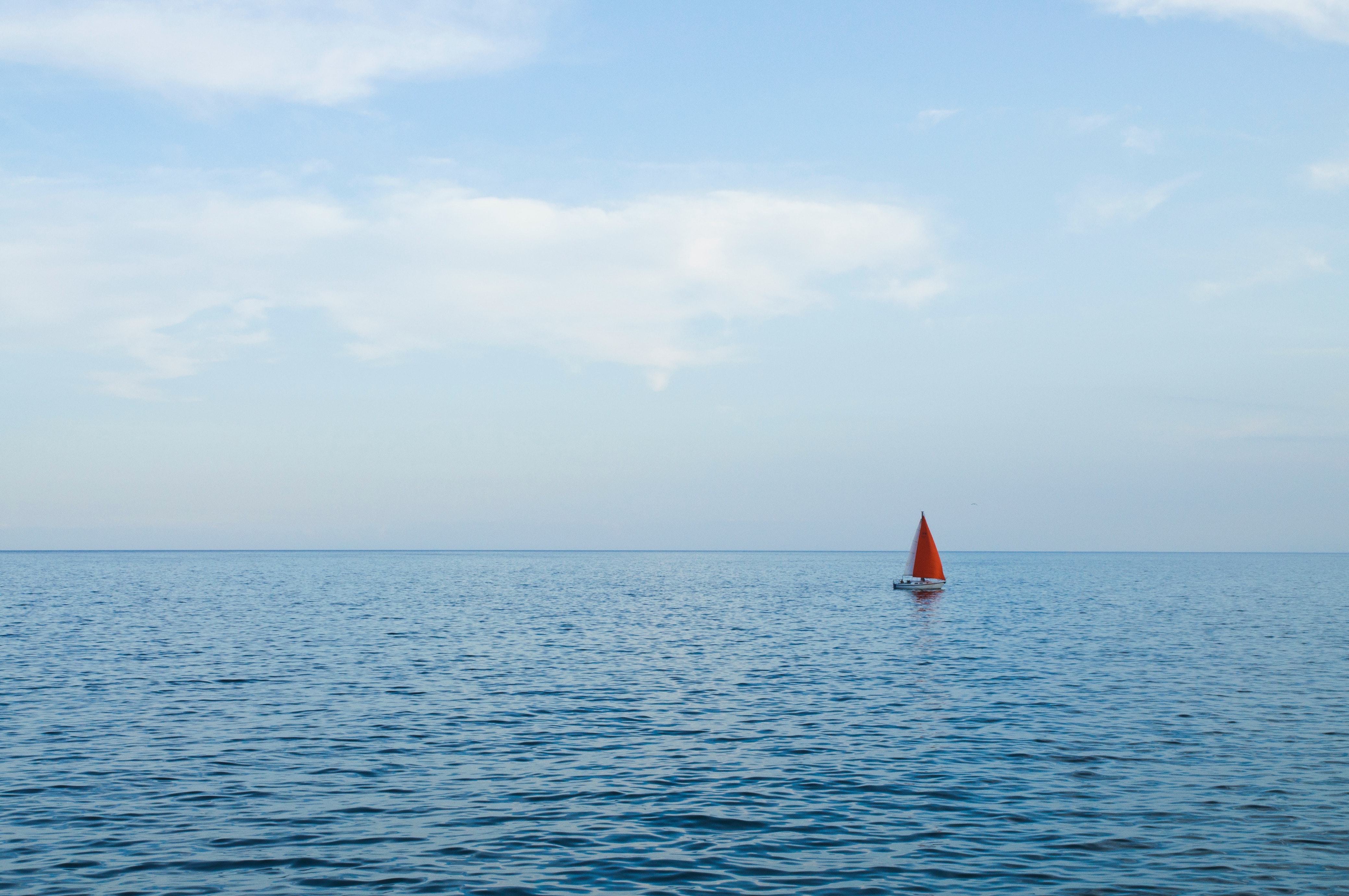 blue ocean with a red sailing boat