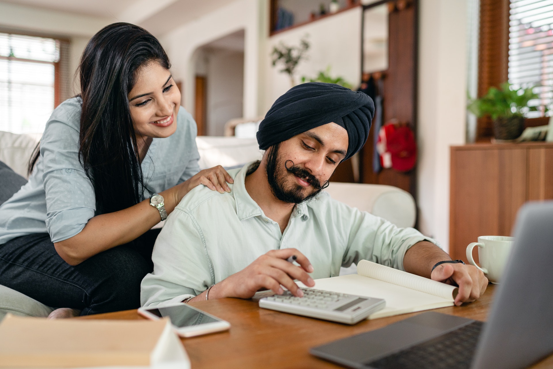 Man with turban and woman working with calculator and notebook