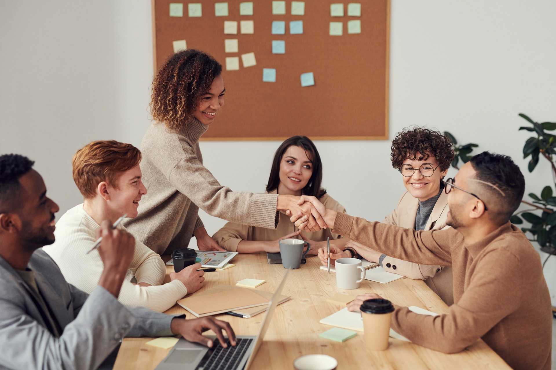 People sitting around a table collaborating and shaking hands